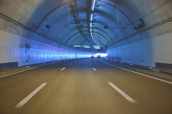 Modern, well-lit motorway tunnel with blue illuminated walls and a clear asphalt road, Zurich,