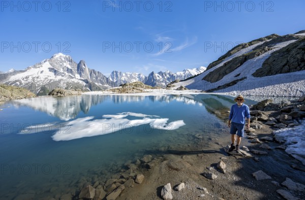 Mountaineer in front of mountain landscape with mountain lake, tourist at Lac Blanc with water