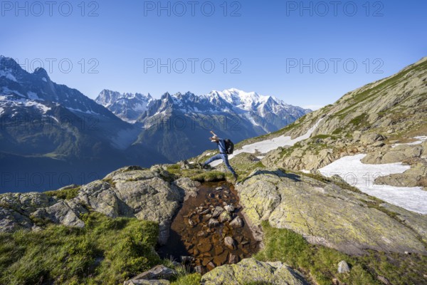 Mountaineer jumping, mountain panorama, view of mountain peaks Grandes Jorasses and Mont Blanc,