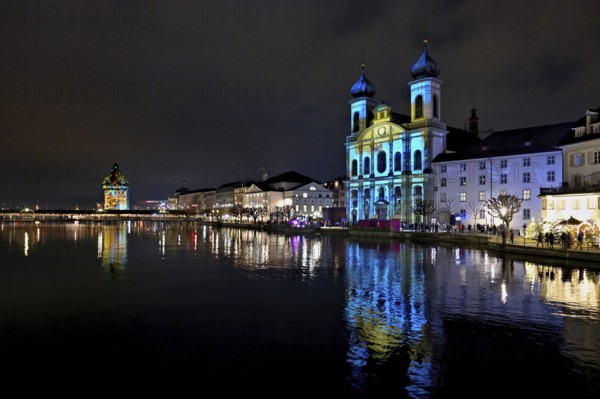 Water tower and Jesuit church on the right with light installation, on the Reuss at dusk, Old Town,