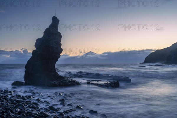 Before sunrise on the beach at Playa de La Caleta. Rocks and sea. Tenerife and the Teide in the