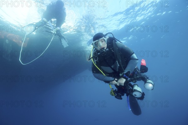 Diver under water with complete equipment waiting until the ladder back to the dive boat is free,
