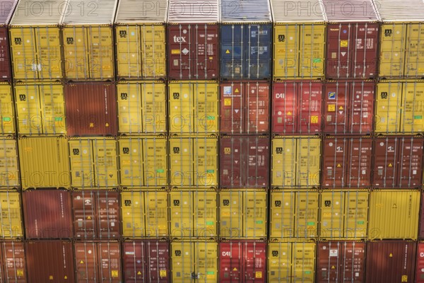 High angle view of stacked yellow and reddish brown MSC, TEX and CAI metal box shipping containers