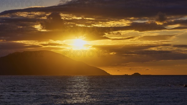 Dramatic golden sunset over the sea with clouds and an island in the background, sunset, Kassos,