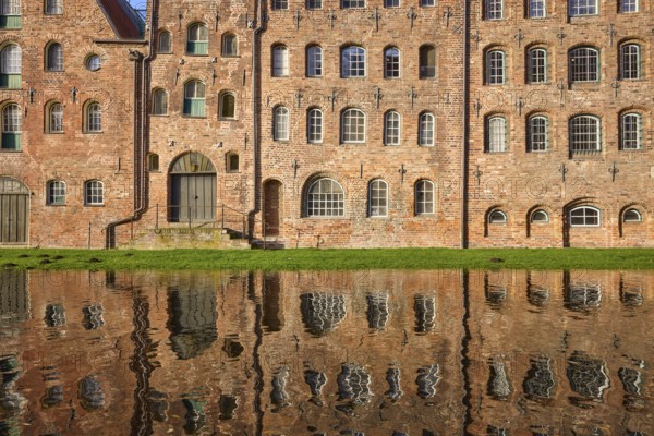 Historic salt storehouse, brick building with windows and doors, reflection on the water surface of