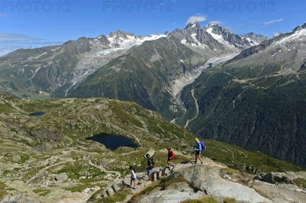 Hikers in the Chamonix hiking area in front of the alpine panorama of the French Alps, from left to