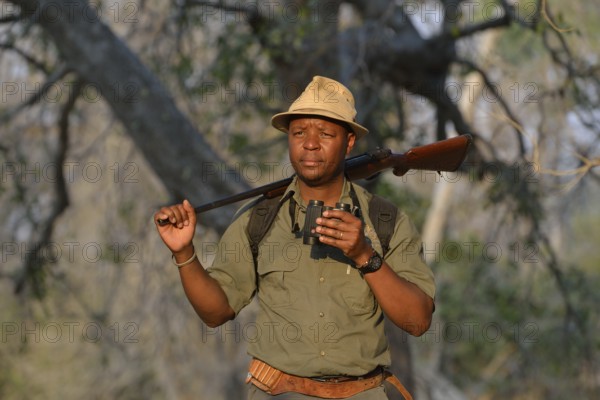 Guide with binoculars and rifle on a walking safari, Mana Pools National Park, Mashonaland West