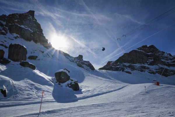 View of a ski resort piste with people skiing in Dolomites in Italy with cable car ski lift. Ski