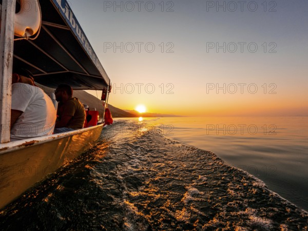 View from below along the orange sunset water of Shkoder Lake in Shiroka from a tourist boat.
