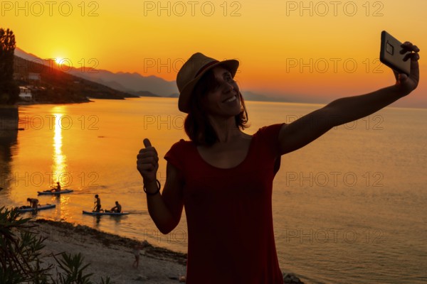 Silhouette of a woman taking a selfie at sunset at Shkoder lake in Shiroka municipality, summer
