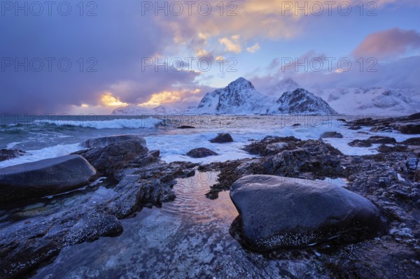 Beach of Norwegian sea on rocky coast in fjord on sunset in winter. Vareid beach, Lofoten islands,