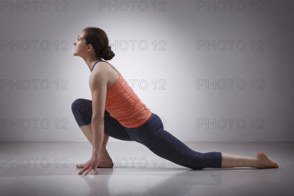 Beautiful sporty fit yogini woman practices yoga asana Anjaneyasana, low crescent lunge pose in