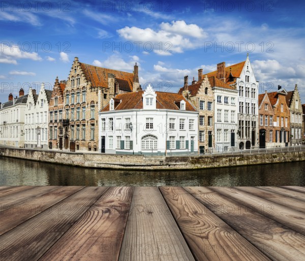 Wooden planks with European view of Bruges canal and old historic houses of medieval architecture