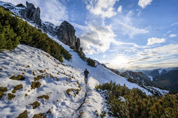 Hikers on a hiking trail with snow, sun star, ascent to Kramerspitz, in autumn, Ammergau Alps,