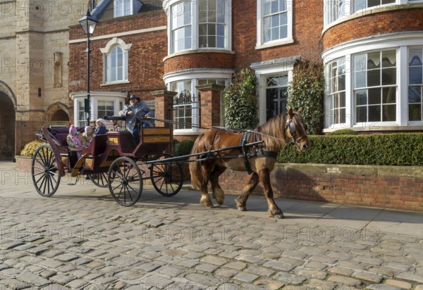 Horse and carriage ride passing houses in Minster Yard of Lincoln cathedral, city of Lincoln,
