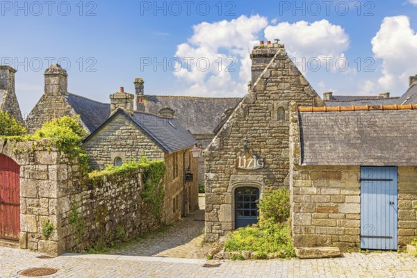 Alley in an old idyllic french villages with picturesque stone houses with lush green garden