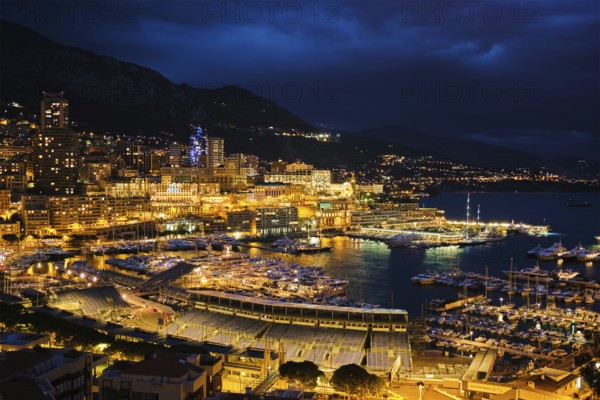Aerial view of Monaco Monte Carlo harbour and illuminated city skyline in the evening blue hour