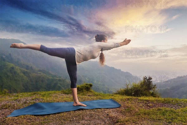 Yoga outdoors, sporty fit woman doing Ashtanga Vinyasa Yoga asana Virabhadrasana 3 Warrior pose