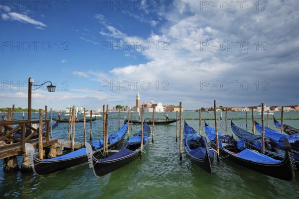 VENICE, ITALY, JUNE 27, 2018: Gondolas and gondolier in lagoon of Venice by Saint Mark (San Marco)