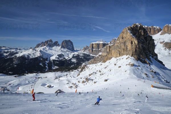 View of a ski resort piste with people skiing in Dolomites in Italy. Ski area Belvedere. Canazei,