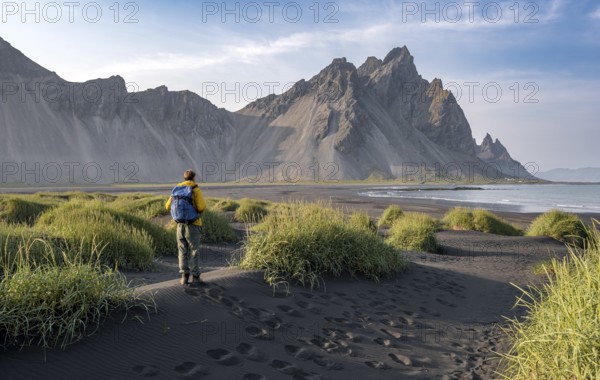 Tourist on a sand dune, Black beach with volcanic sand, Sand beach, Dunes with grass, Stokksnes
