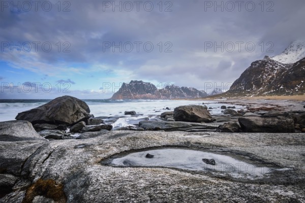 Rocks on beach of fjord of Norwegian sea in winter with snow. Utakliev beach, Lofoten islands,