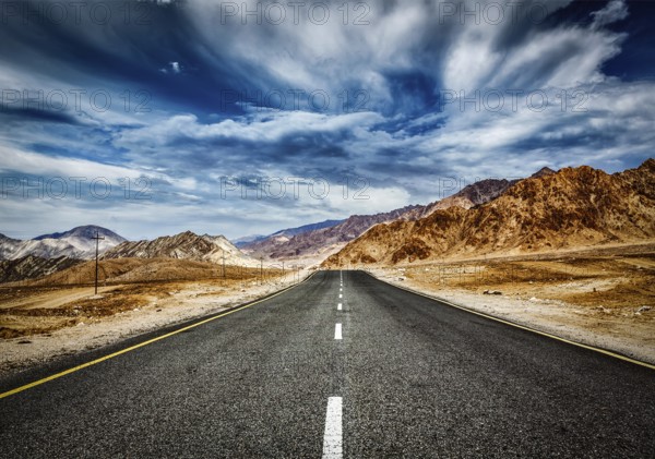 Travel forward concept background, road in Himalayas mountains and dramatic clouds. Ladakh, Jammu