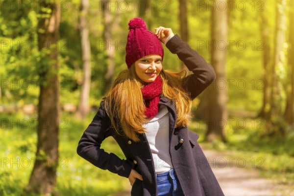 Latin girl with a black jacket, scarf and red woolen hat enjoying in an autumn park, smiling