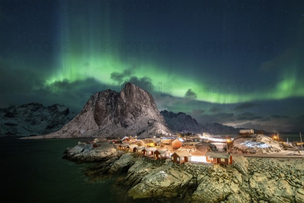 Northern Lights (Aurora Borealis) over Rorbuer Huts of Hamnoy, snowy mountains behind, Hamnøy,