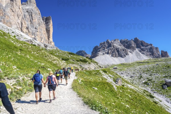 Tourists enjoying a scenic hike on the tre cime di lavaredo trail amidst the breathtaking mountain