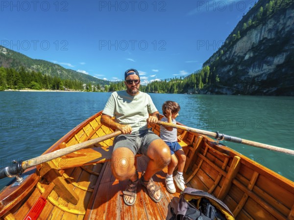 Tourists rowing a wooden boat on lake braies, surrounded by stunning mountain scenery in the