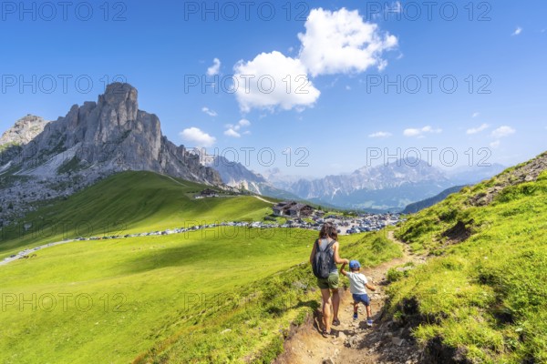 Mother and son hiking on a sunny day in the italian dolomites at giau pass, enjoying the