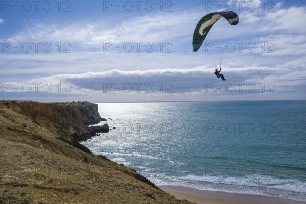 Sagres, Algarve, Portugal - Paraglider flying on the town beach Praia da Mareta, at the back left