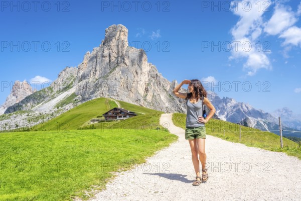Female tourist enjoying summer vacation hiking in dolomites, italy, walking on path near mountain
