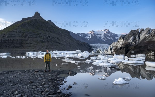 Hikers at a lake, reflection in the Svínafellslon glacier lagoon with ice floes, Svínasfellsjökull