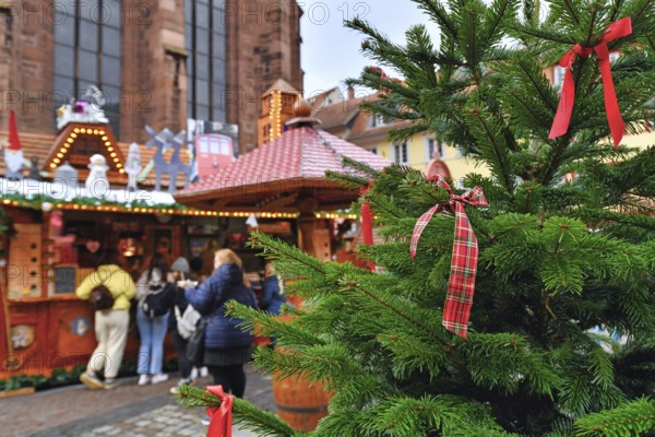 Heidelberg, Germany, December 2019: Close up of red ribbon tied to Christmas tree with sales booth