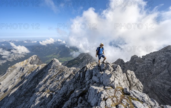Mountaineer on a rocky narrow mountain path with mountain panorama, mountain tour to the summit of