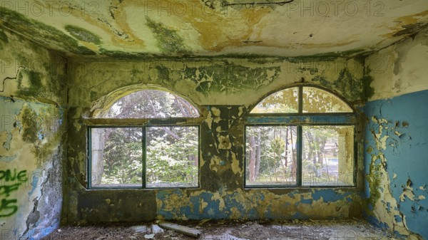 Dilapidated arched windows in an abandoned building with traces of decay and blue walls, Lost