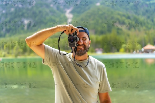 Tourist taking pictures with vintage camera at lake dobbiaco, surrounded by the breathtaking