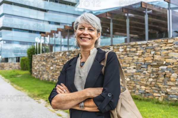 Portrait of a smiling mature businesswoman standing proud with arms crossed outdoors in a financial