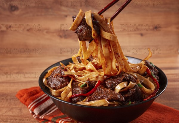 Udon noodles with beef in Mongolian style, with green onions and vegetables, served in a black