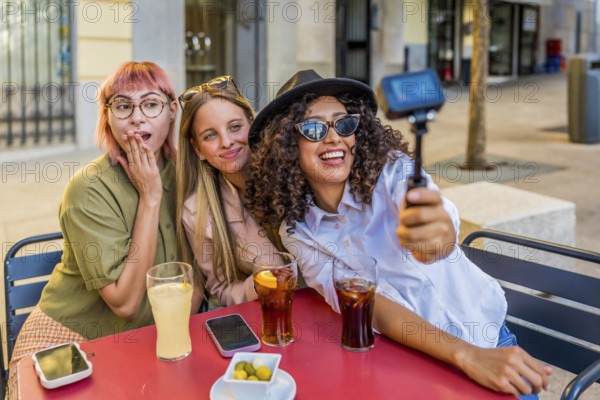 Latin beauty Woman recording video with camera while sitting with friends on a terrace drinking