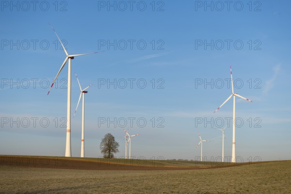 Several wind turbines rotating over a wide field, sustainable energy generation shown, solar park,