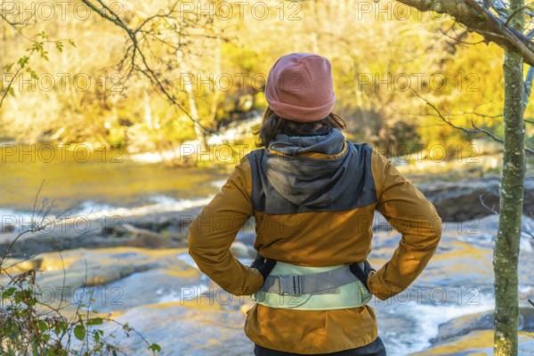 Hiker admiring the serene zaldibartxo pool in gorbeia natural park on a sunny autumn day,