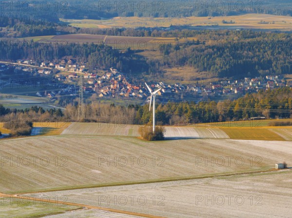 A wind turbine stands in a frosty landscape with a village in the background, district of Calw,