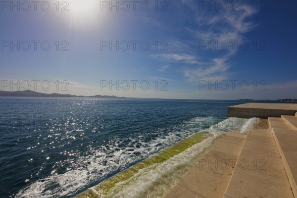 Steps lead to the clear sea under bright sunshine and blue sky, a calm coastal atmosphere, sea