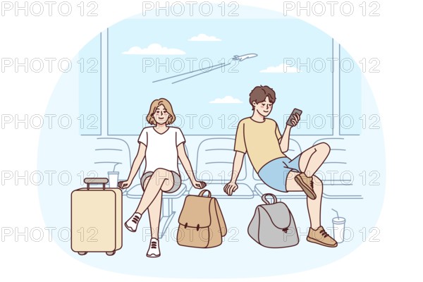 Happy couple with suitcases sitting in airport ready for summer vacation. Smiling man and woman