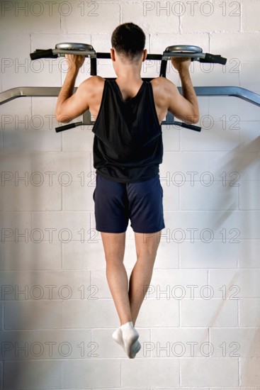 A young man performs exercises to strengthen his back in a gym, supervised by an instructor. This