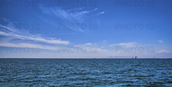 Panoramic beautiful seascape on a bright summer day with few sailing boats afar, great sky with