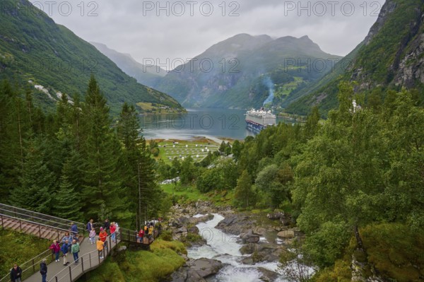 An impressive landscape with a raging waterfall, surrounded by green mountains and forests, with a